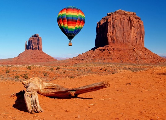 A dinosaur and a hot air balloon in the desert
