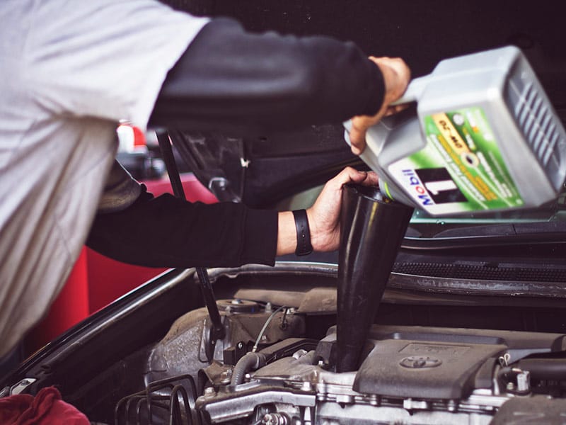 A person pouring oil into a car

Description automatically generated with low confidence