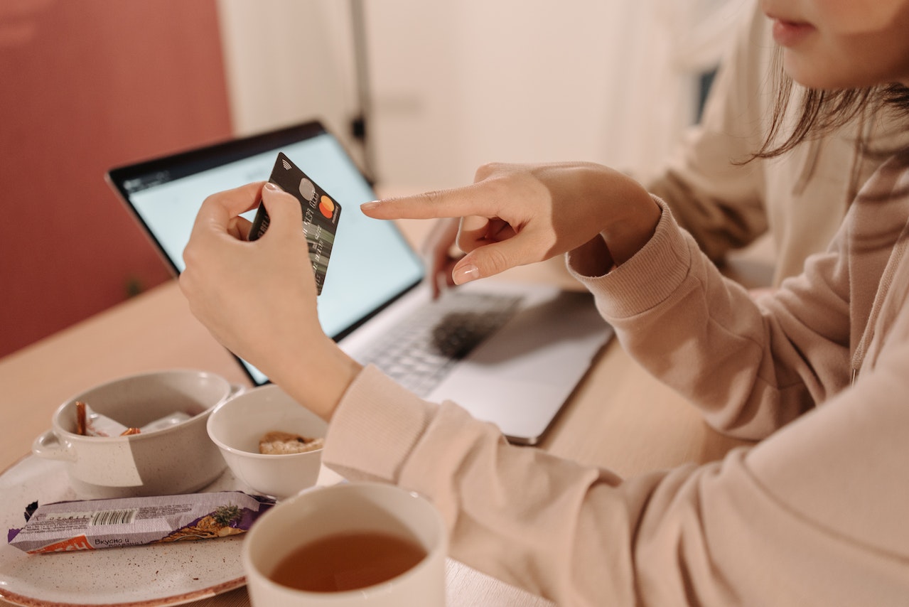 a person with a laptop pointing at a credit card