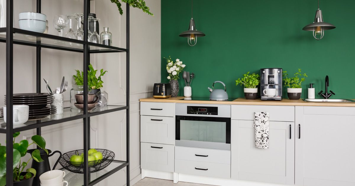 A kitchen with white cabinets and green walls

Description automatically generated