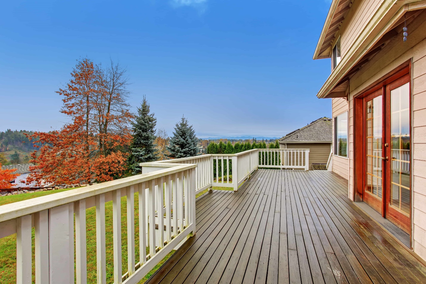 A deck with a white railing and trees in the background

Description automatically generated