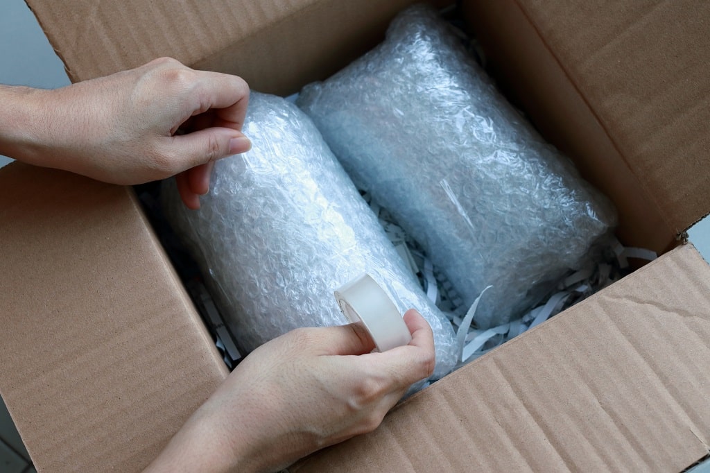 Hands packing a box with bubble wrap