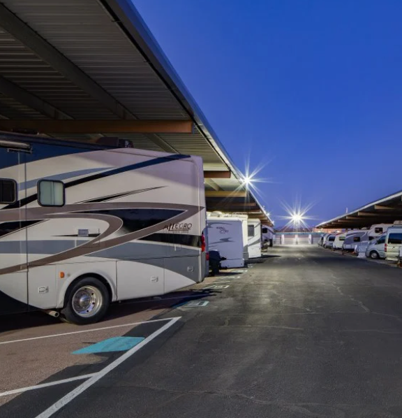 RV's parked at covered well lit lot at night.
