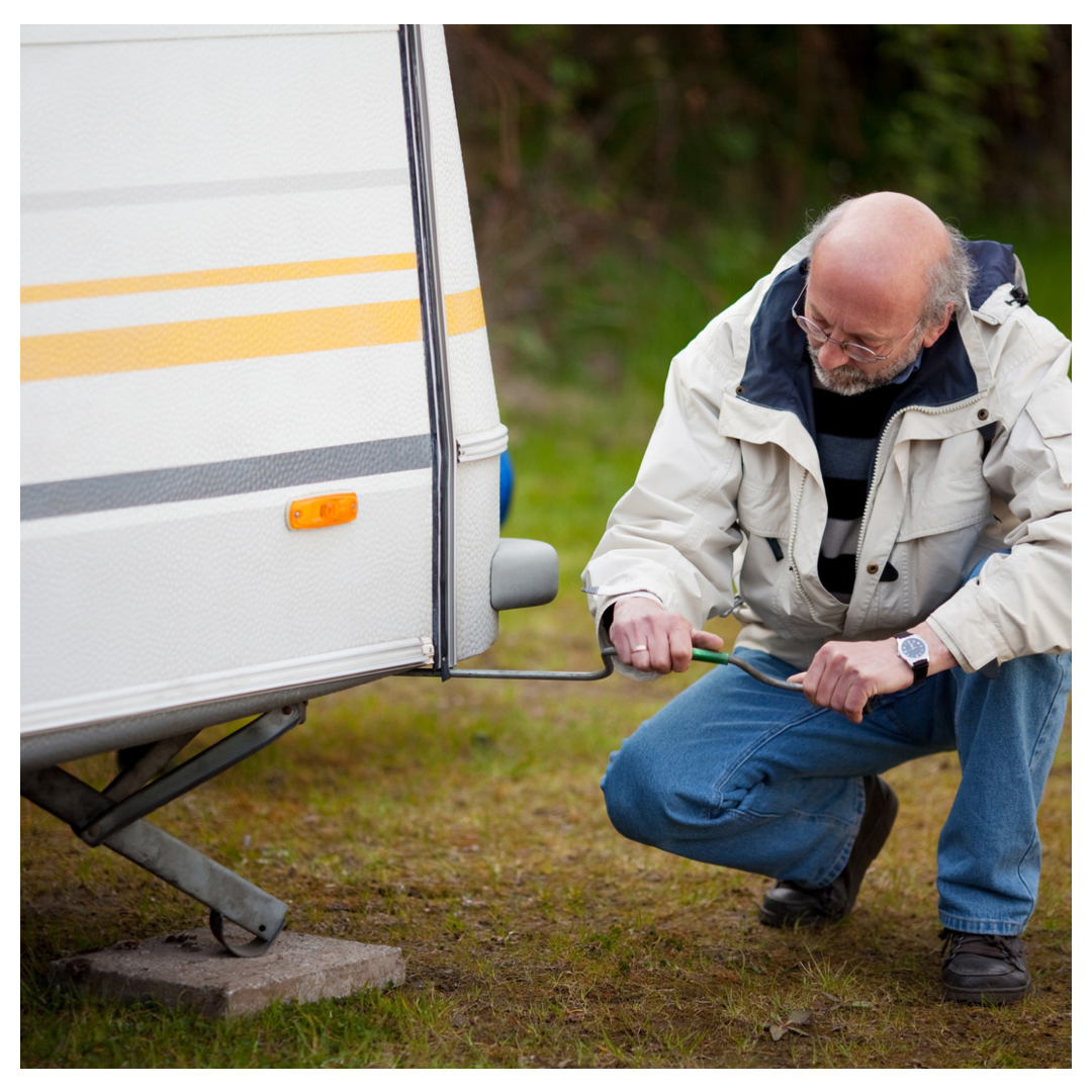Man using jack to lift RV.
