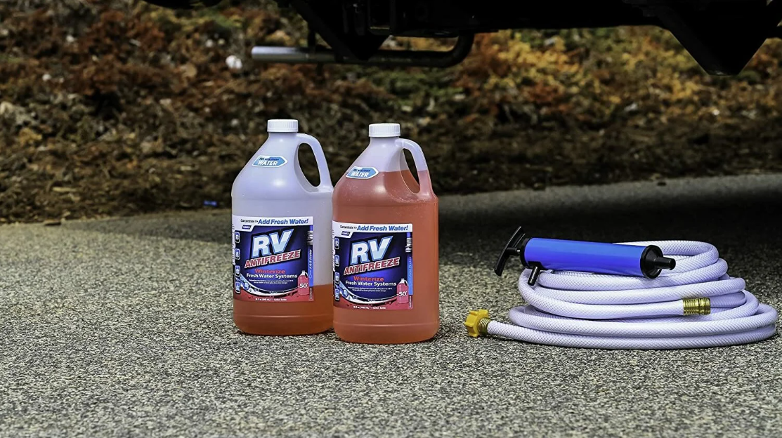 A couple bottles or RV anti-freeze sitting next to a hose and a pump.