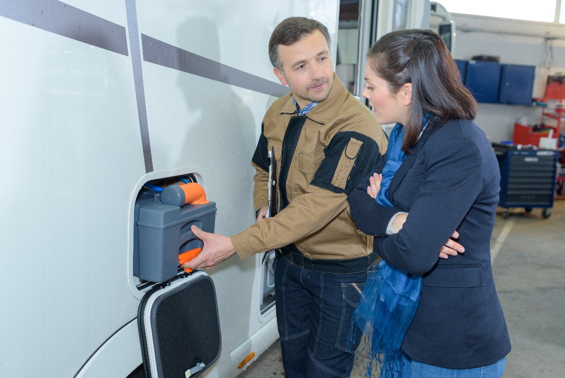 A man showing a woman the battery in her RV and how to disconnect it.