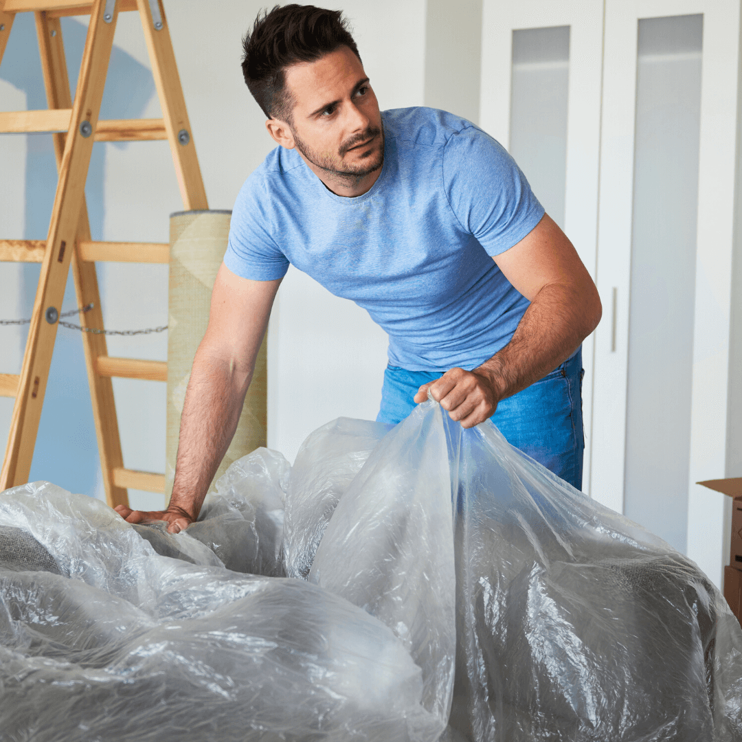 man putting plastic wrap over his furniture